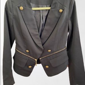 Fitted black jacket with gold zip and button accents.